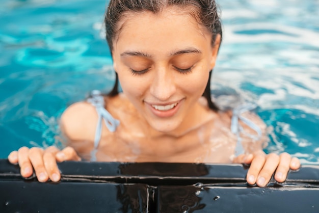 Jovem descansando na beira da piscina