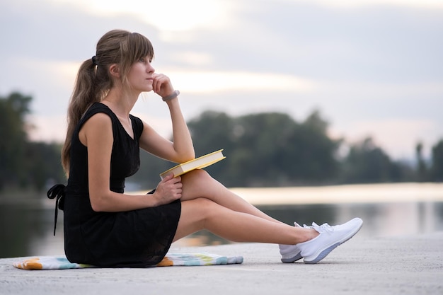 Jovem descansando no parque de verão lendo um livro Conceito de educação e sudy