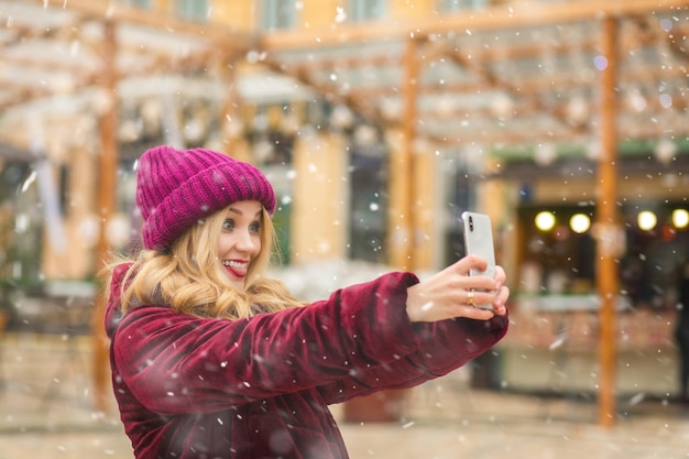 Jovem descolada tirando uma selfie no mercado de rua de inverno
