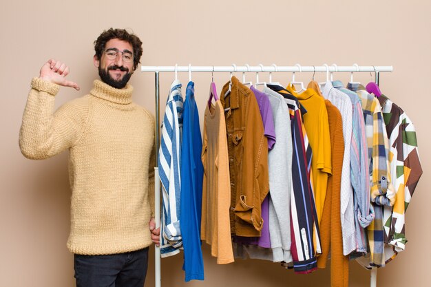 Jovem descolado com uma cela com roupas contra uma parede plana