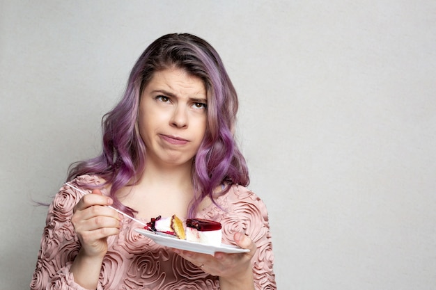 Foto jovem desconcertada comendo bolo de queijo doce com frutas. espaço para texto