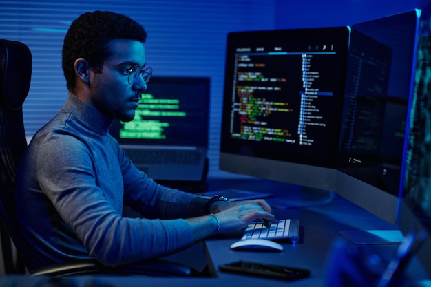 Foto jovem desenvolvedor de software sério trabalhando na frente de monitores de computador