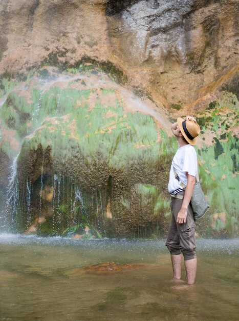 Jovem desfrutando de um parque natural na base da grande cachoeira