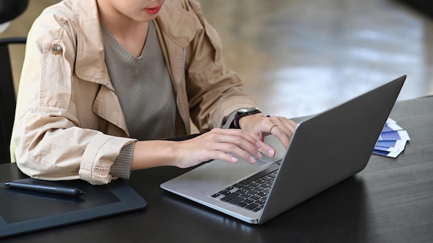 Jovem designer gráfico feminino trabalhando com computador portátil no escritório criativo