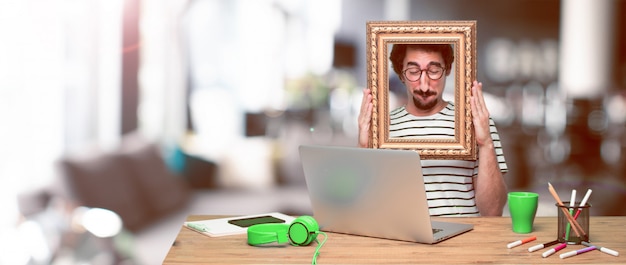 Foto jovem designer gráfico louco em uma mesa com um laptop