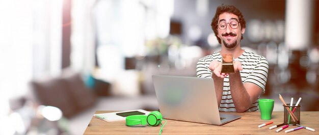 Jovem designer gráfico louco em uma mesa com um laptop