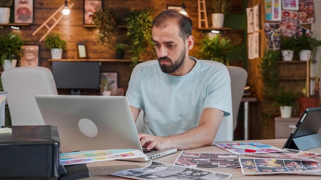 Jovem designer trabalhando em um laptop em um espaço criativo e aconchegante. Agência criativa e espaço de trabalho bacana