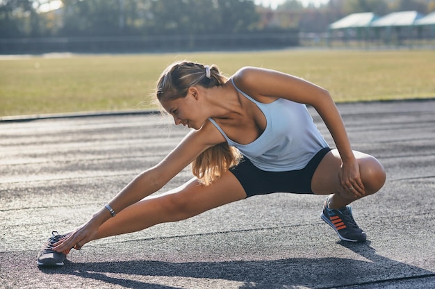 Jovem desportista esticando e se preparando para correr.