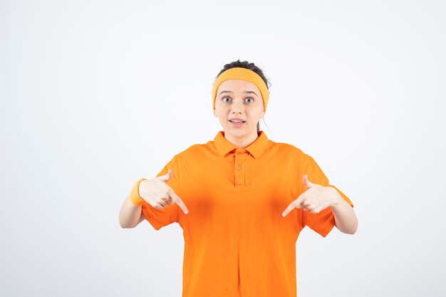 jovem desportista vestida de laranja em pé e olhando.