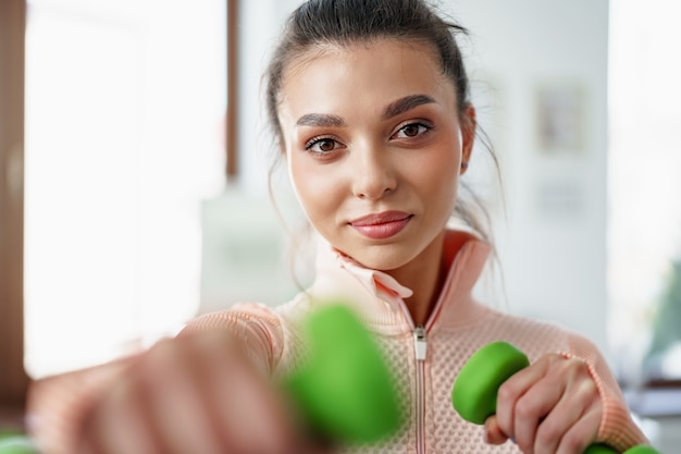 Jovem desportiva a fazer exercício em casa com halteres