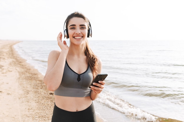 Jovem desportiva alegre a correr na praia