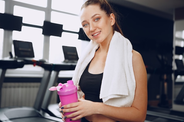 Jovem desportiva tomando uma bebida em uma academia após o treino