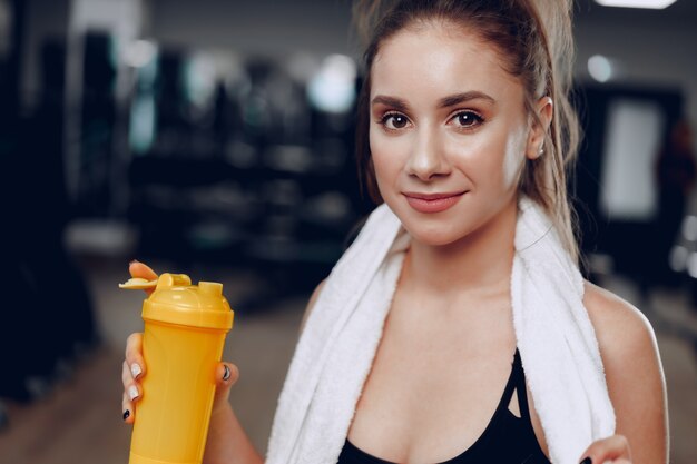 Jovem desportiva tomando uma bebida em uma academia após o treino