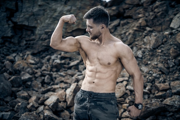 Jovem desportivo posando com abs perfeito ao ar livre. Olhando para o lado. Corpo musculoso sem camisa. Fechar-se.