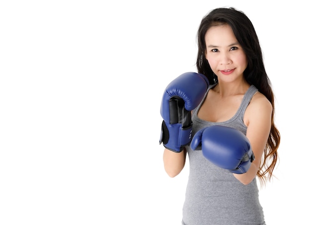 Jovem determinado em forma de mulher asiática com luvas de boxe azuis, em posição de combate e olhando para a câmera com um sorriso contra um fundo branco