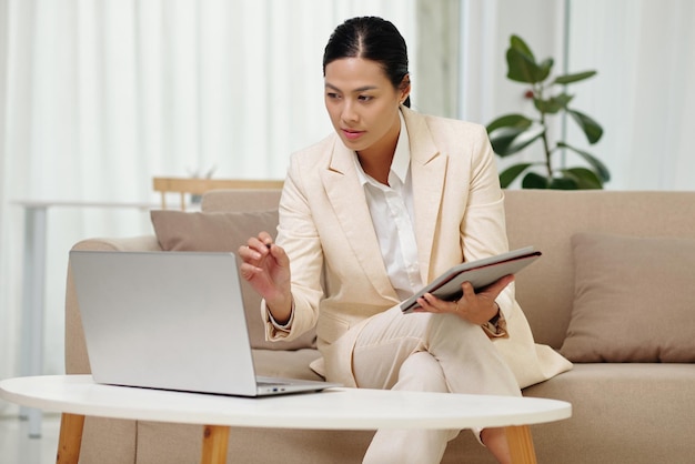 Jovem diretor executivo confiante com tablet olhando para a tela do laptop