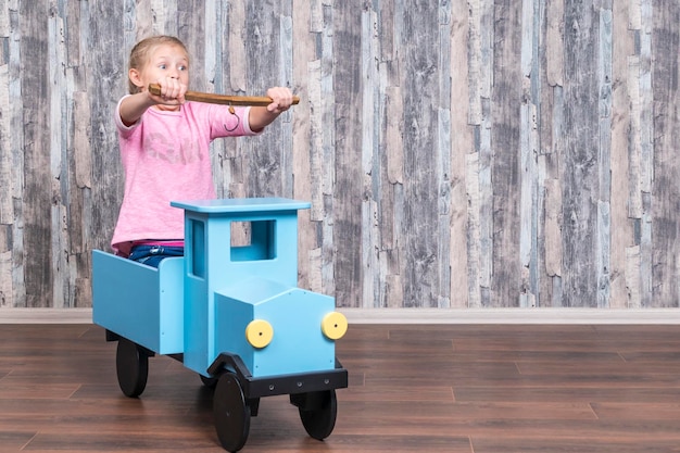 jovem dirige emocionalmente um caminhão de brinquedo de madeira com uma vara