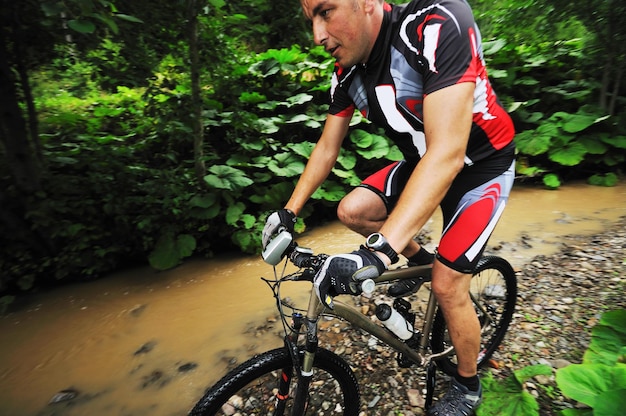 jovem dirigindo mountain bike sobre o rio de água