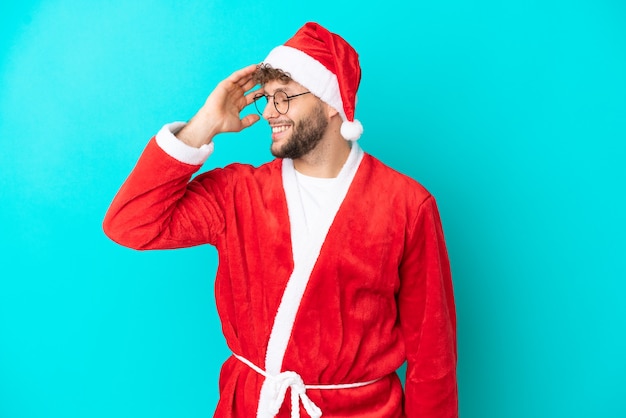 Jovem disfarçado de Papai Noel isolado em um fundo azul percebeu algo e pretende a solução