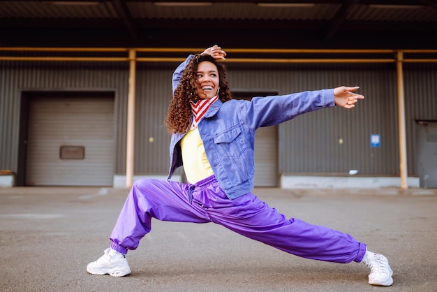 Jovem divertida com bandana americana dançando sozinha na rua Dança esportiva e cultura urbana