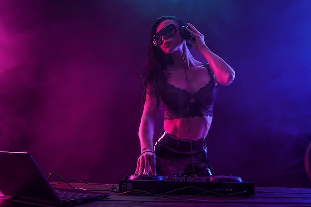 Jovem DJ sexy com óculos de sol tocando música