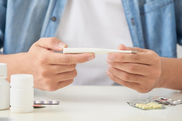 Jovem doente olhando para um termômetro