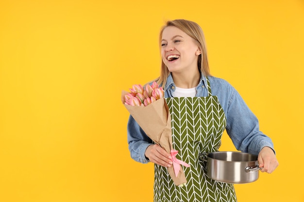 Jovem dona de casa com buquê de flores em fundo amarelo