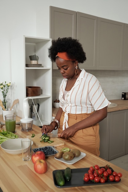 Jovem dona de casa cozinhando salada de legumes na cozinha