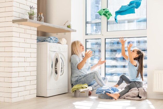 Jovem dona de casa e garotinha lavando roupa juntos