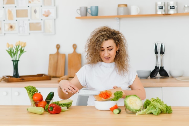 Jovem dona de casa feliz misturando salada de legumes