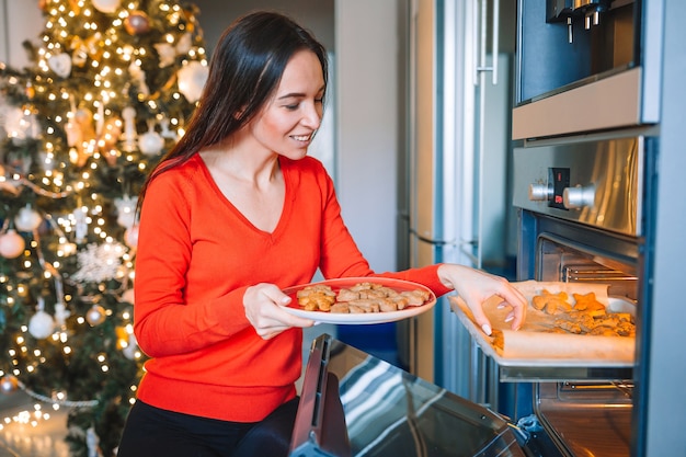 Jovem dona de casa feliz preparando biscoito de gengibre no natal em casa