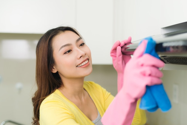 Jovem dona de casa usando luvas de borracha limpando cozinha