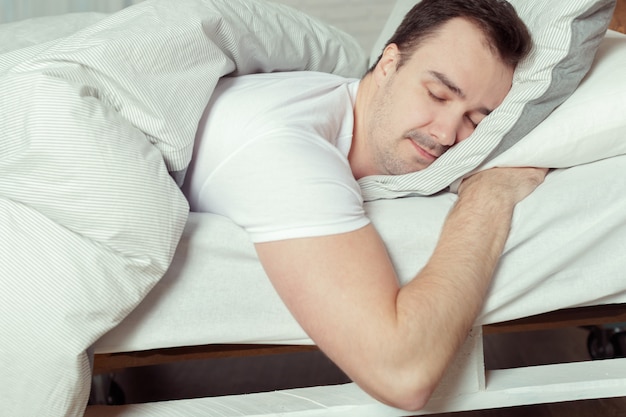 Jovem dormindo na cama no quarto