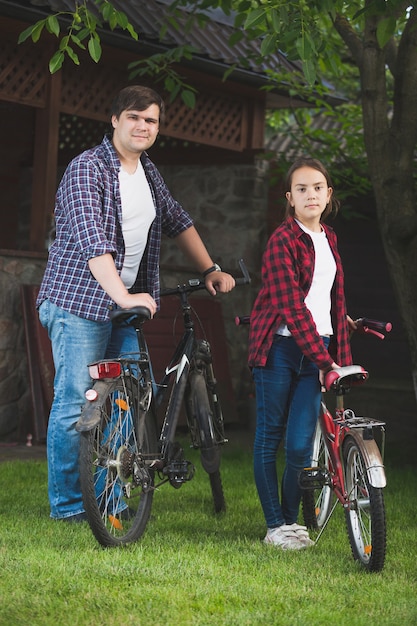 Jovem e adolescente posando com bicicletas no parque