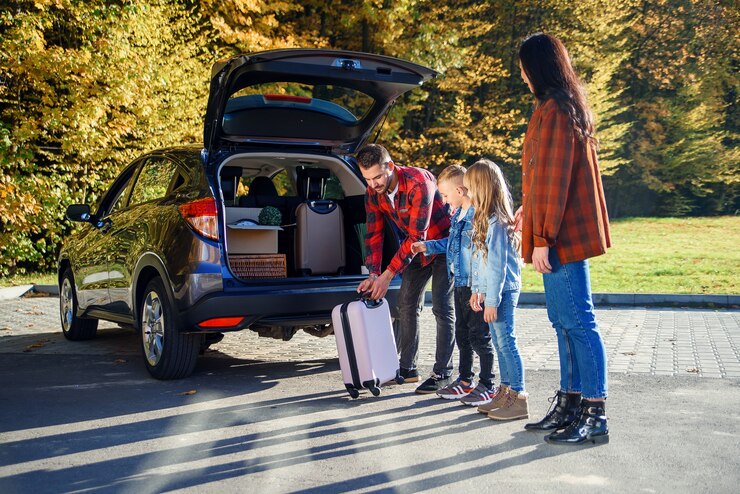 Jovem e adorável família carregando o carro