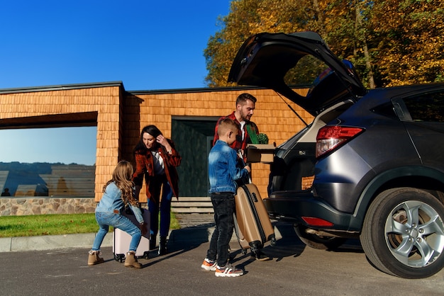 Jovem e adorável família carregando o carro