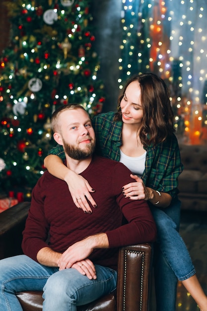 Jovem e adorável família, marido e mulher na árvore de natal