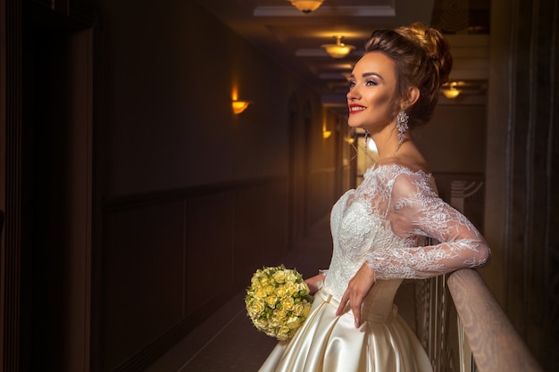 Jovem e alegre noiva loira sorrindo e olhando para o lado em um vestido de noiva