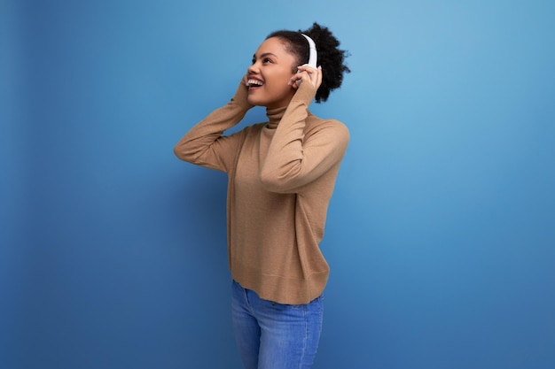 Jovem e atraente amante da música latina com rabo de cavalo afro preto com fones de ouvido