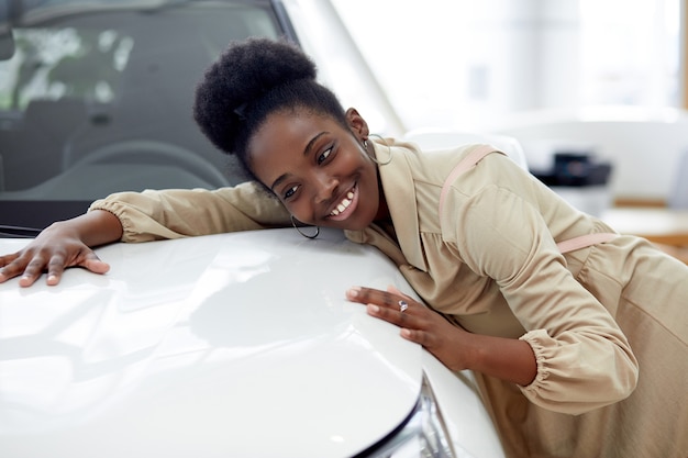 Foto jovem e atraente mulher afro adora ser dona de um automóvel novo