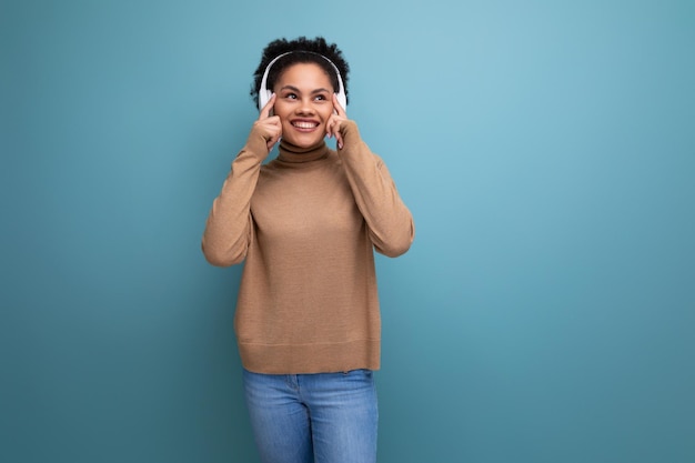 Jovem e bela amante da música hispânica com cabelo afro encaracolado em roupas casuais ouve música