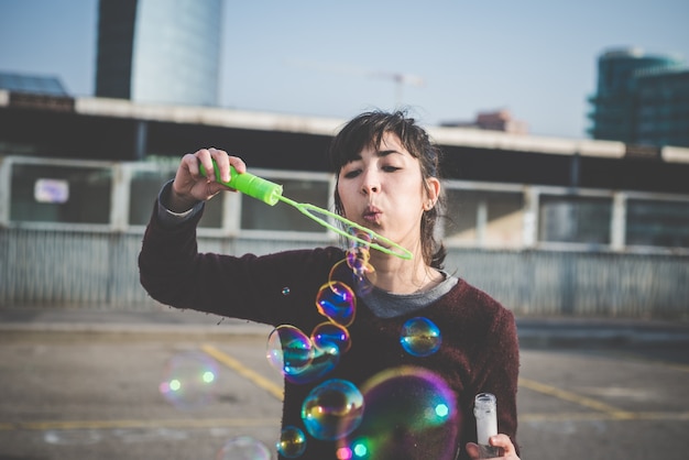 jovem e bela bela sopradora de bolhas de mulher de hipster