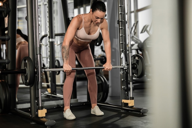 Jovem e bela caucasiana em forma de mulher forte fazendo exercícios na academia