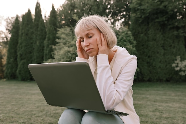 Jovem e bela empresária trabalhando em um laptop freelancer trabalha na natureza Empresária no trabalho ao ar livre