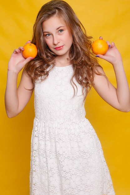 Jovem e bela modelo engraçado com uma fatia de laranja em fundo laranja. com maquiagem e penteado. segurando limão com um belo sorriso.