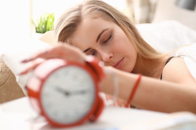 Jovem e bela mulher acordando com o conceito de alarme matinal