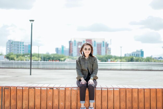 Jovem e bela mulher asiática vestindo jaqueta e calça jeans preta posando ao ar livre