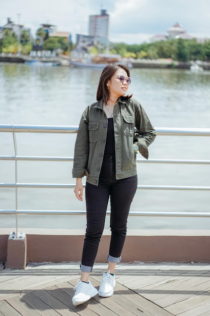 Jovem e bela mulher asiática vestindo jaqueta e calça jeans preta posando ao ar livre