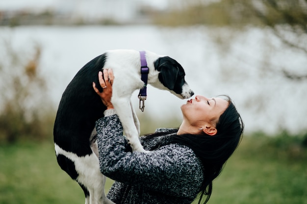 Jovem e bela mulher beijando o cachorro ao ar livre.