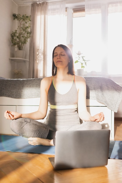 Jovem e bela mulher caucasiana fazendo ioga e meditação em casa